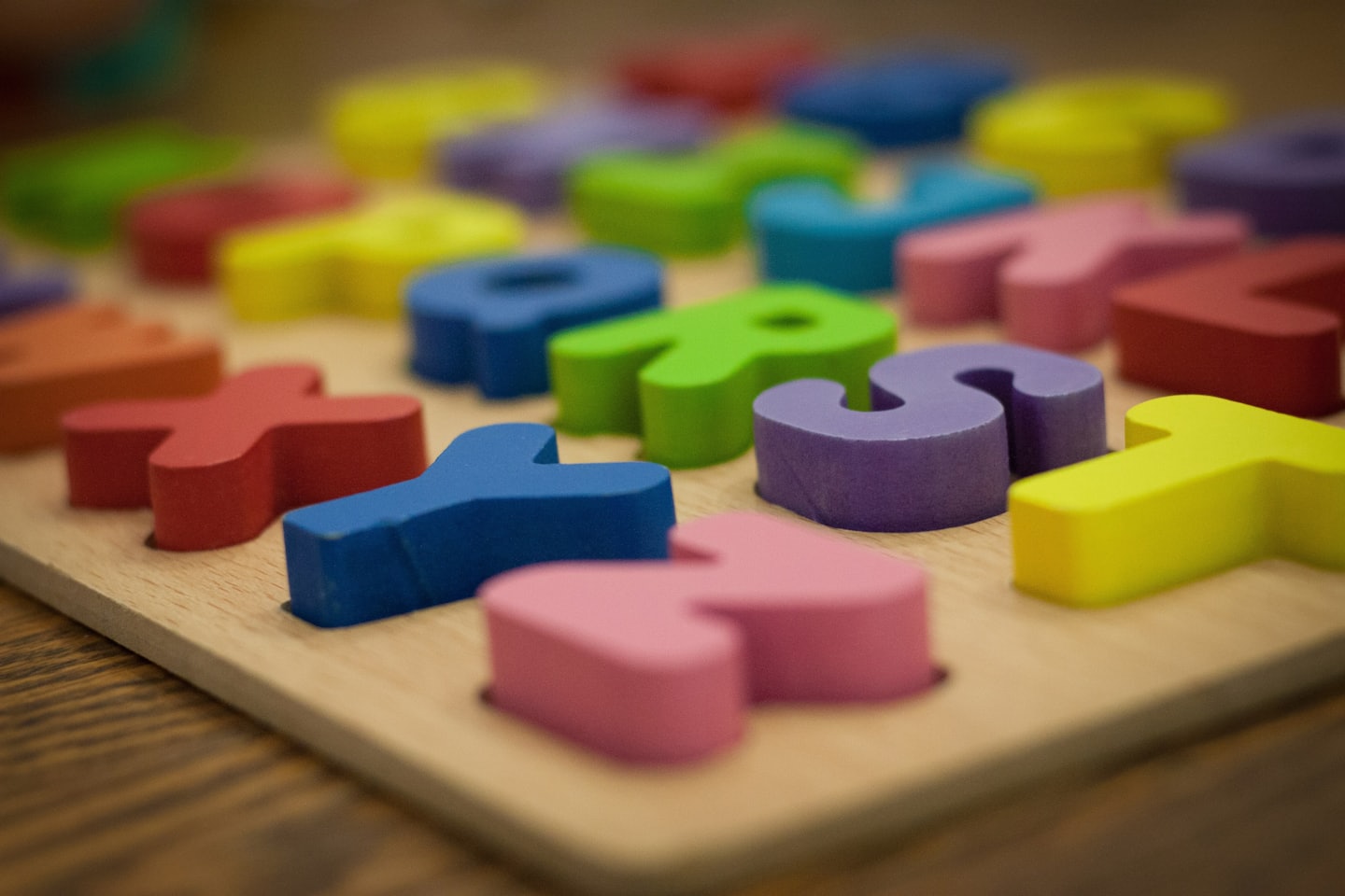 Wooden alphabet puzzle with colorful letters inserted.