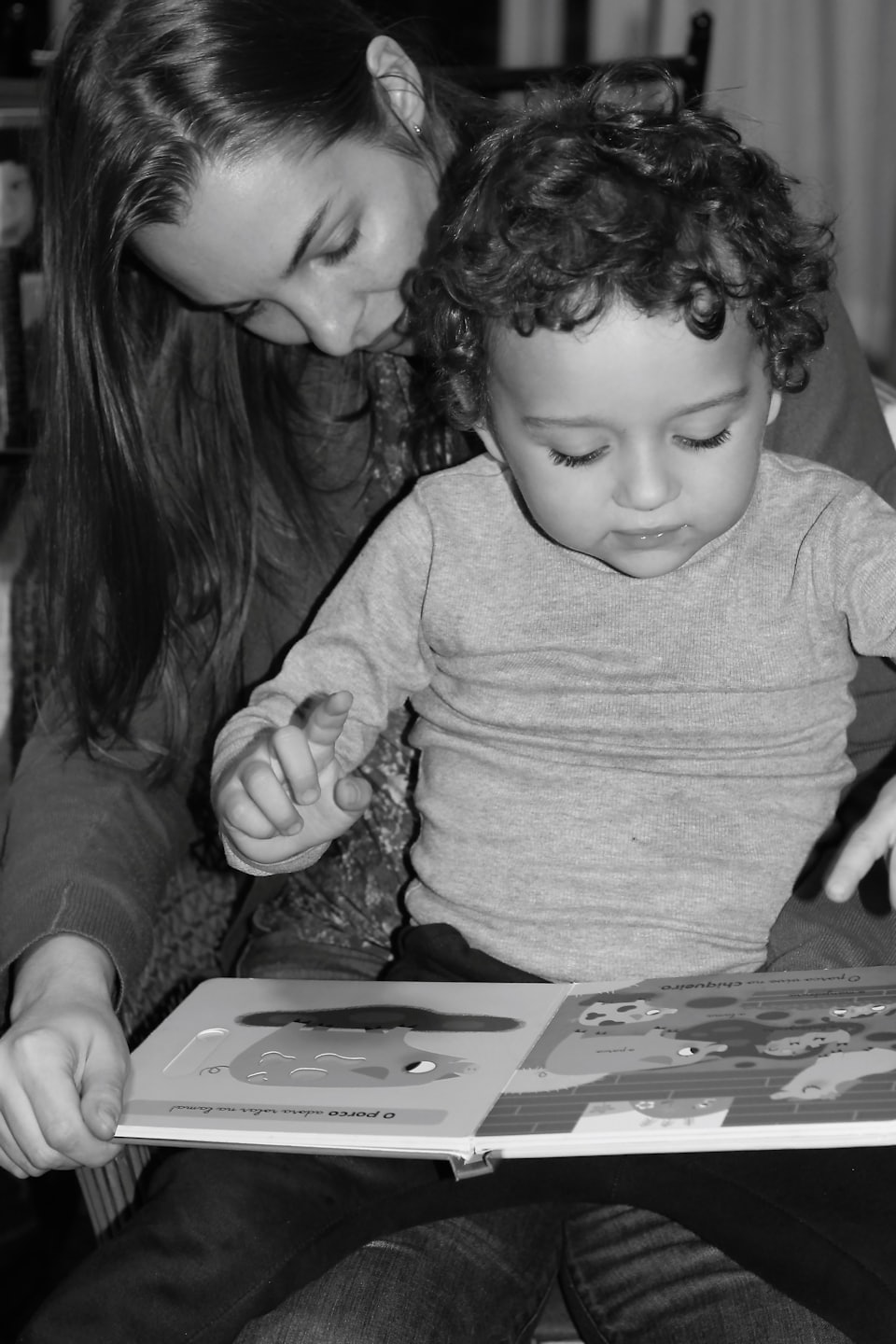 Woman and child reading a book together at home.